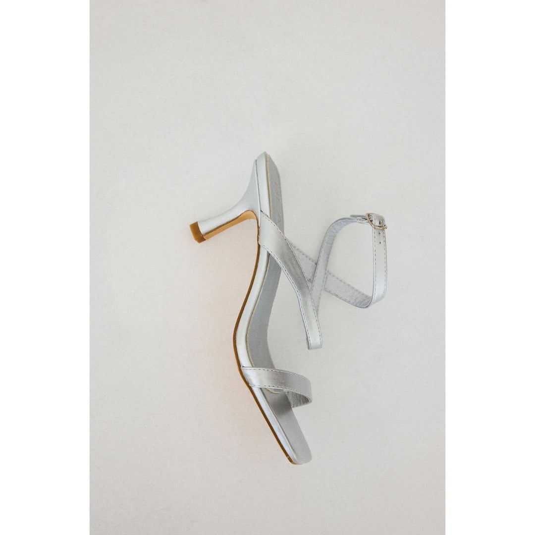 Silver high-heeled sandal on a light gray background.