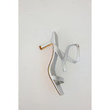 Silver high-heeled sandal on a light gray background.