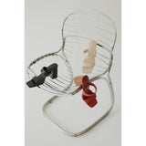 Three women's heeled sandals in red, black, and beige on a metal wire chair.