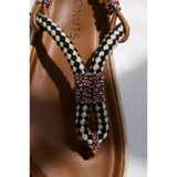 Close-up of a sandal with a checkered strap and colorful knot on a white background.