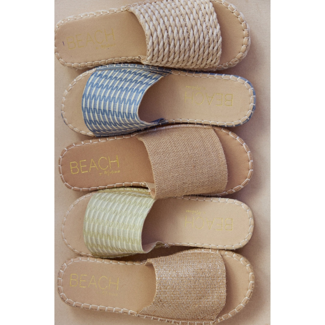 Stack of five espadrille sandals with 'Beach by Matisse' branding on a beige background.