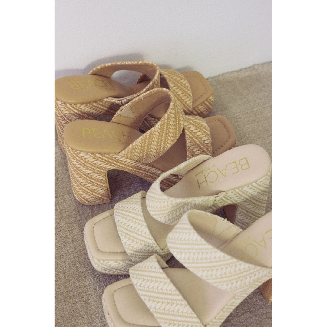 Two pairs of woven high-heeled platform sandals with 'Beach by Matisse' branding on a textured surface with a neutral background.
