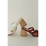 Two high-heeled sandals with woven design on a light background.