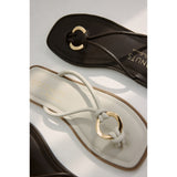 Dark brownand white sandals with gold accents on a light gray background.