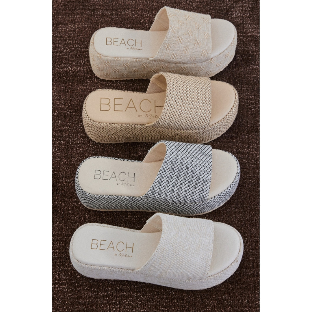 Four pairs of 'Beach by Matisse' sandals in different patterns on a brown carpet.