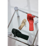 Three shoes (black, beige, red) on a white surface with a reflective background.