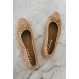 Pair of brown woven flats on a marble surface.