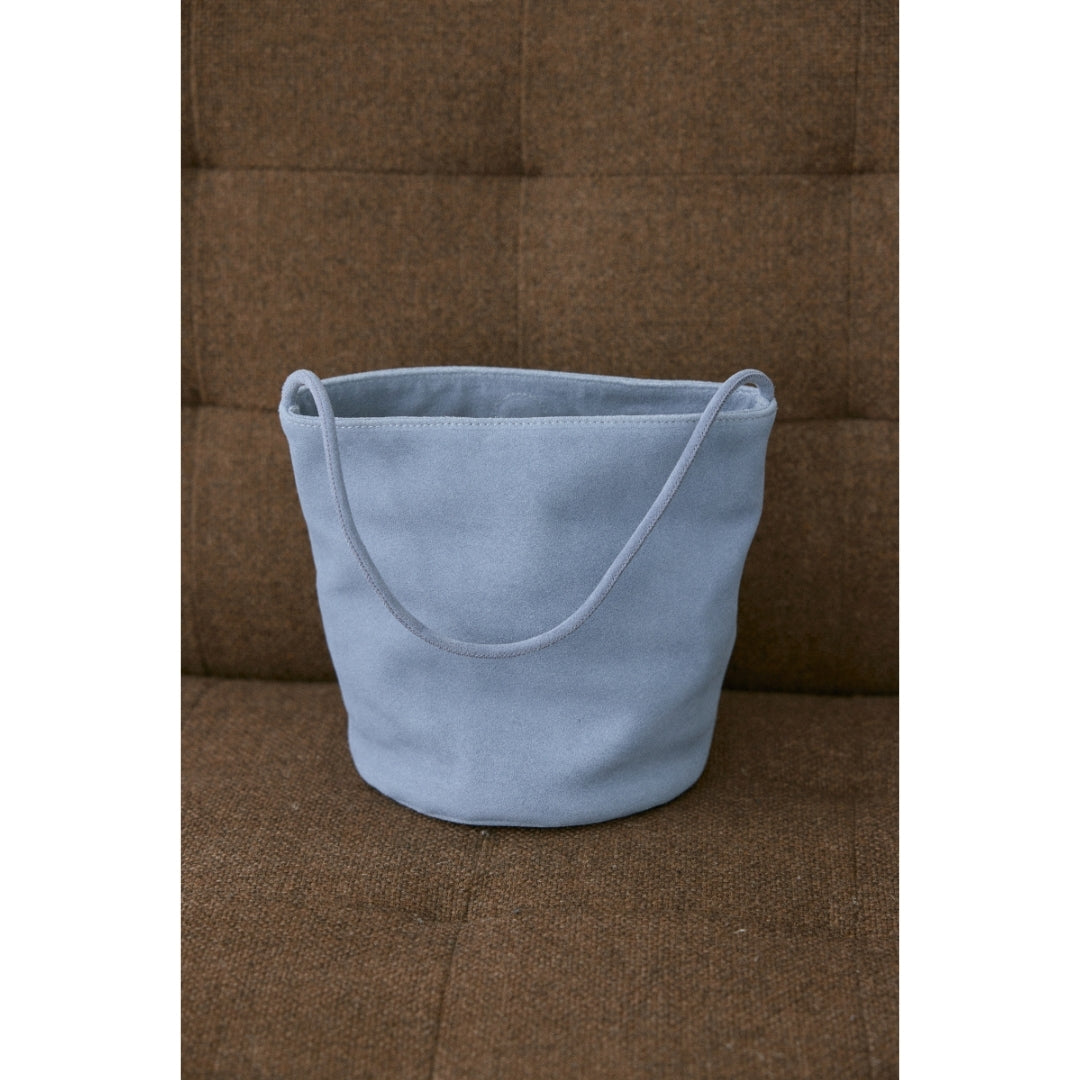 A blue suede handbag sitting on a brown couch.