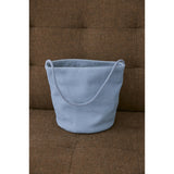 A blue suede handbag sitting on a brown couch.