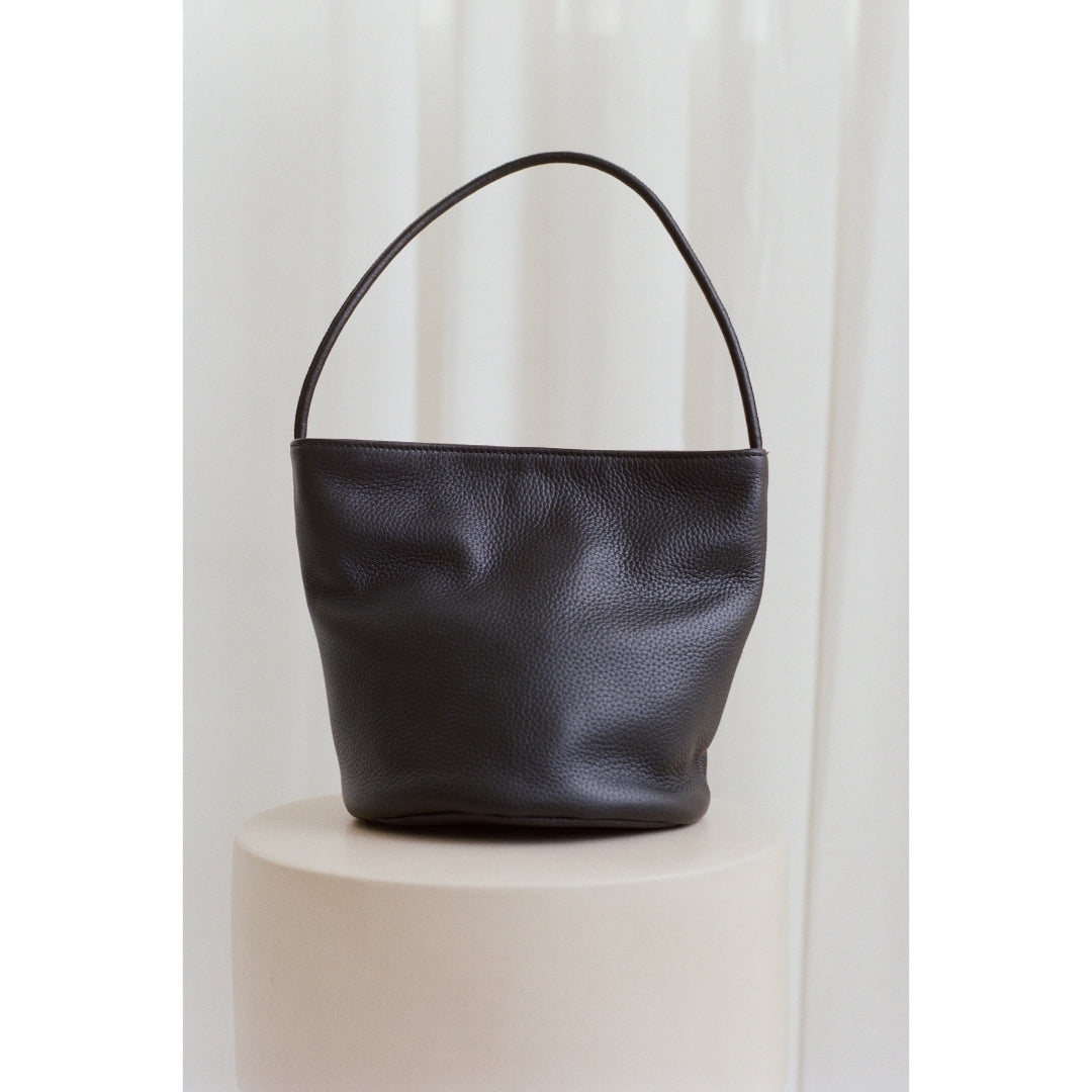 Black leather handbag on a white background.