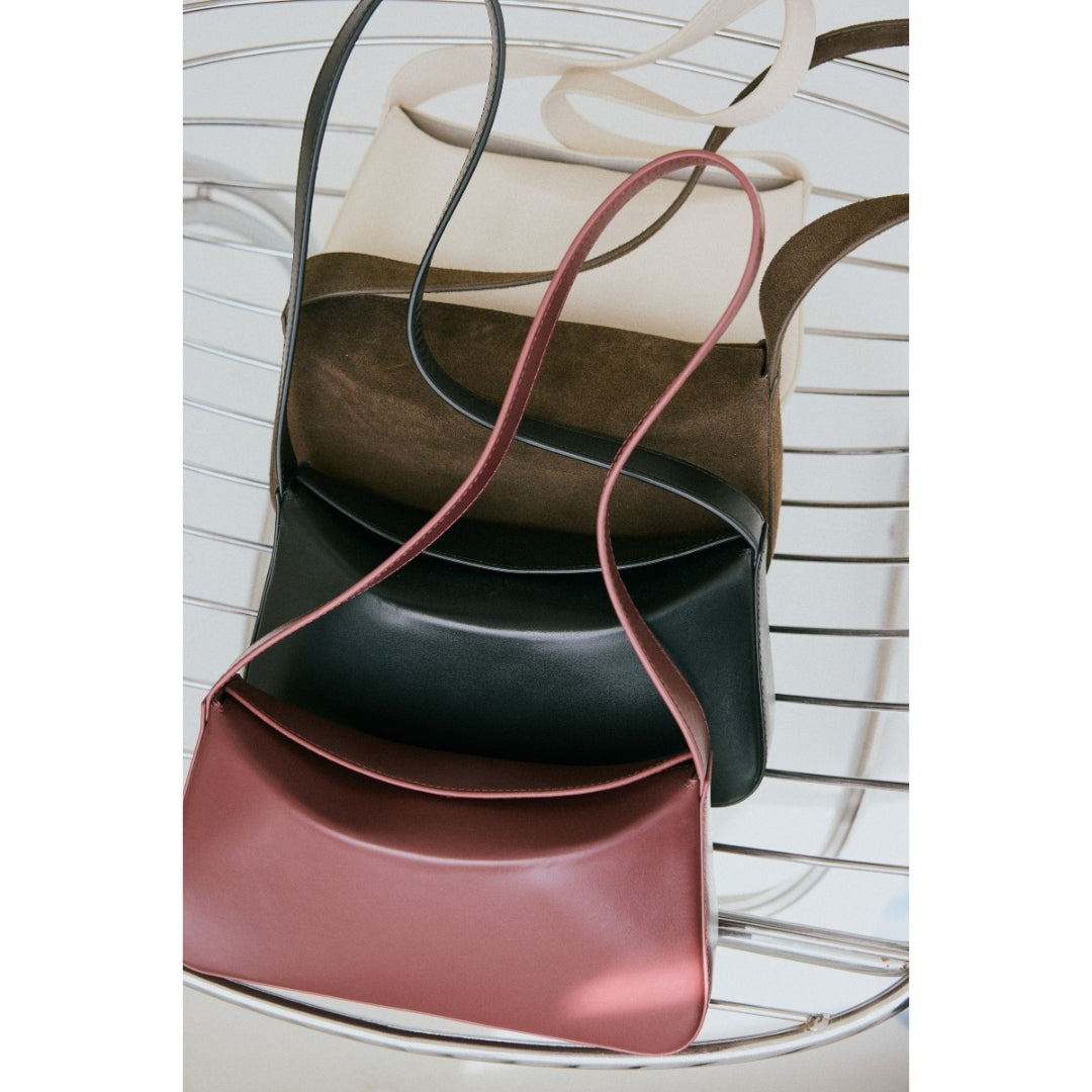 Stack of leather handbags in various colors on a white background.