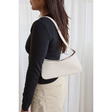 Person wearing a white shoulder bag against a white curtain background.