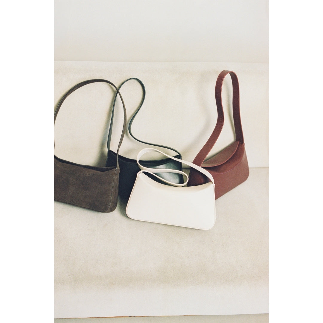 Four handbags in different colors on a light background.