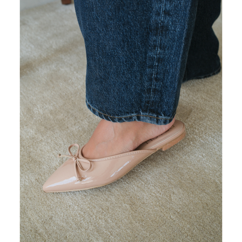 Reggie Vegan Pointed Toe Mule – Beach by Matisse – Beige faux patent leather flat mule with pointed toe and petite bow detail.