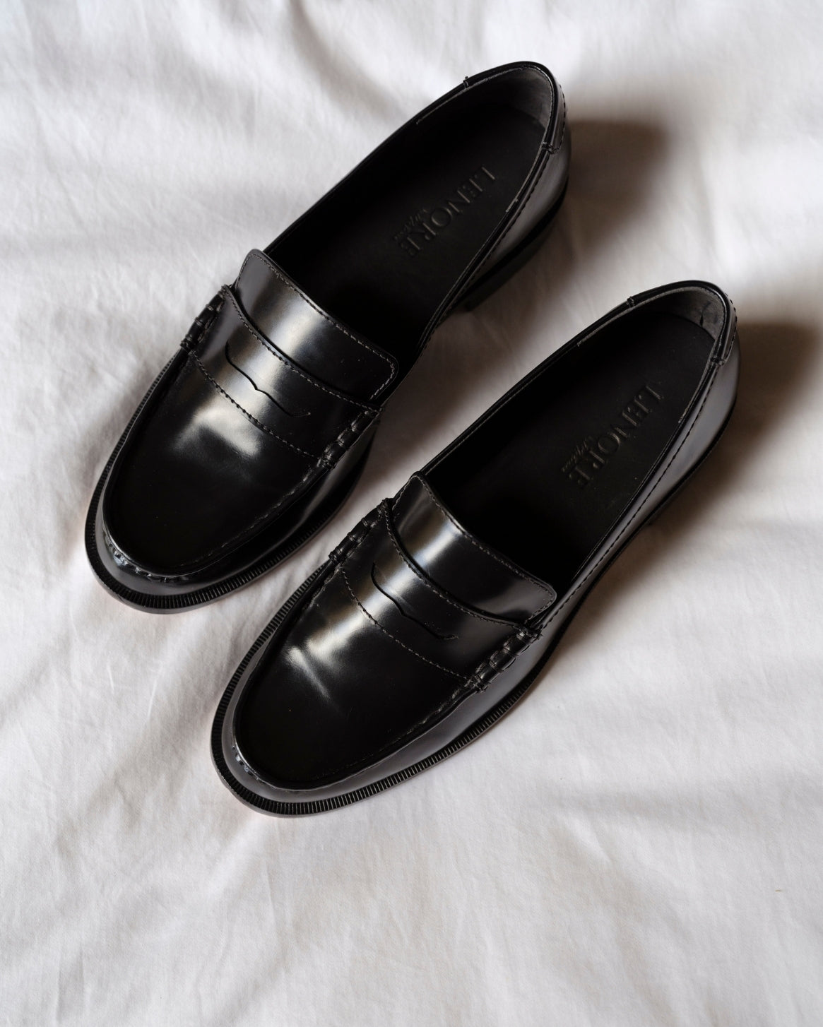 Pair of black loafers on a white fabric background