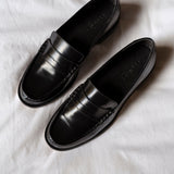 Pair of black loafers on a white fabric background