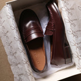 Pair of burgundy loafers in a box with branded tissue paper