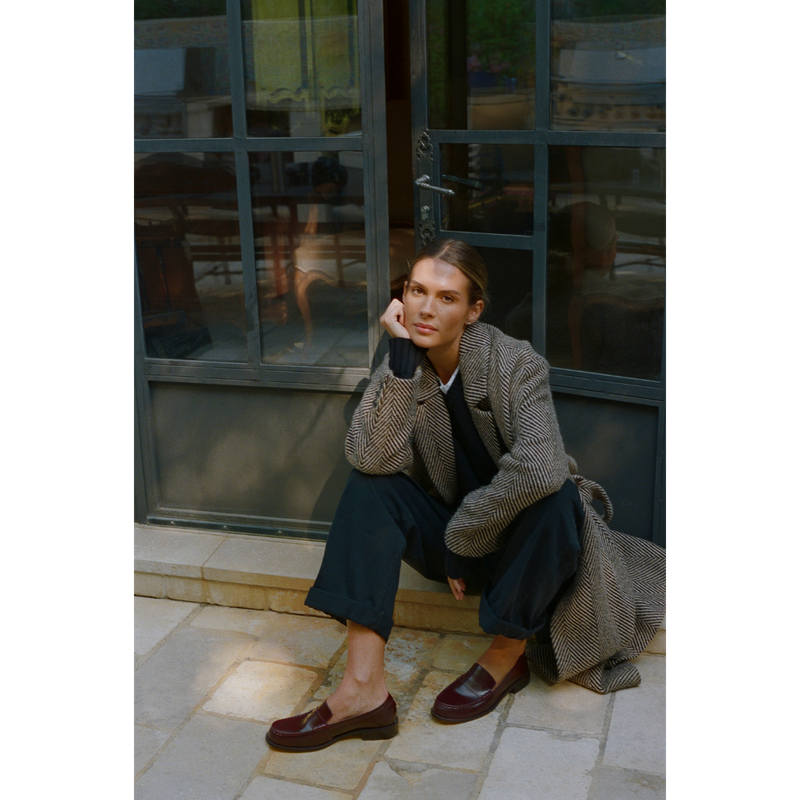 Burgundy leather penny loafers with a polished finish, classic moccasin stitching, and a low stacked heel. A timeless staple for effortless sophistication.