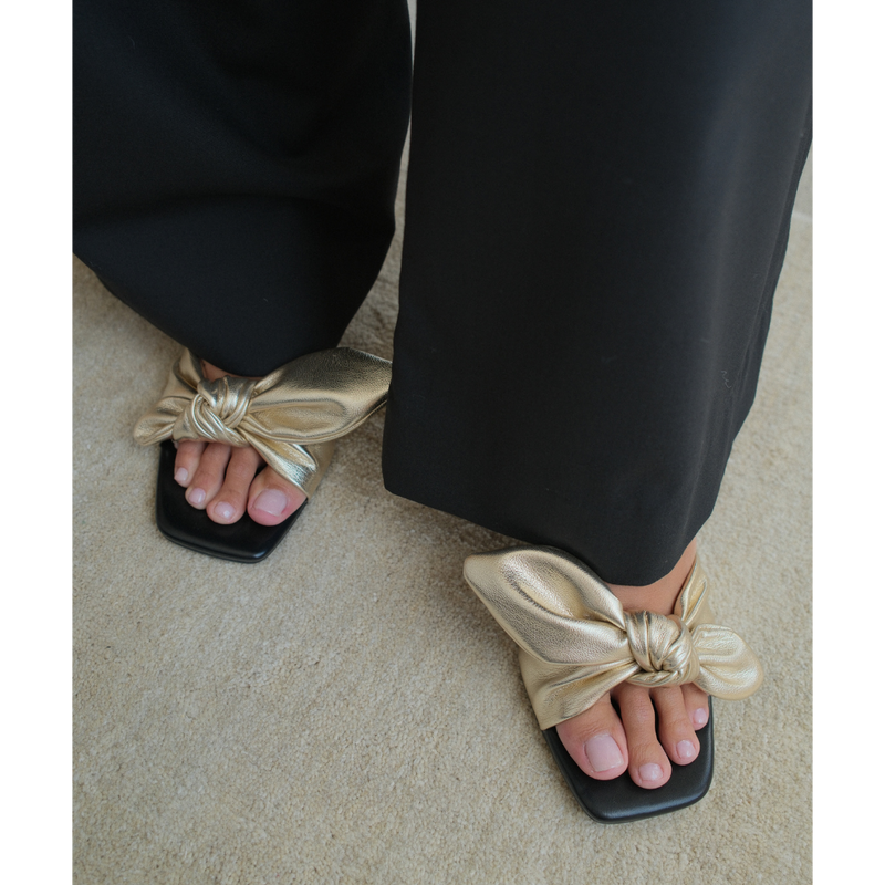 Uptown Vegan Heeled Mule – Coconuts by Matisse – Gold metallic slip-on sandal with square toe, bow detail strap, and tapered kitten heel.